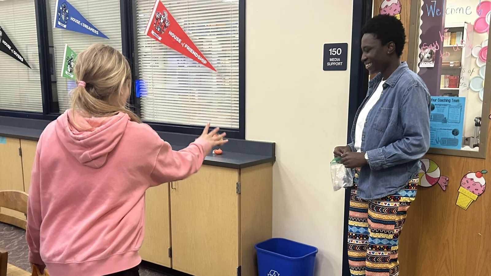 Afia Asamoah helping a student throw a ball into a basket, as part of the activity