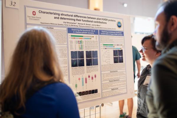 People looking at a research poster during an interdisciplinary graduate program symposium